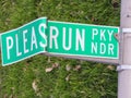 Broken funny road sign bent to look like Please Run or Ã¢â¬ÅPLEASRUNÃ¢â¬Â lying on the grass